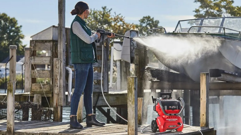 A person using a Craftsman pressure washer on a boat.
