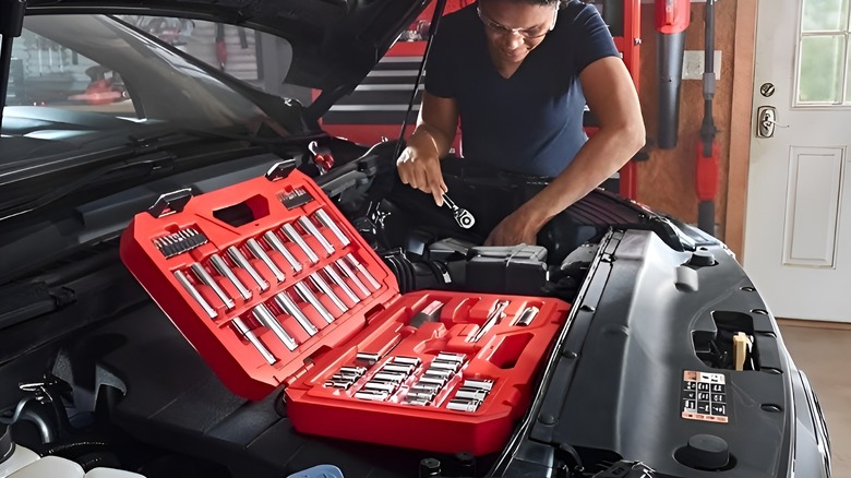 Woman working on car with open case of Craftsman sockets