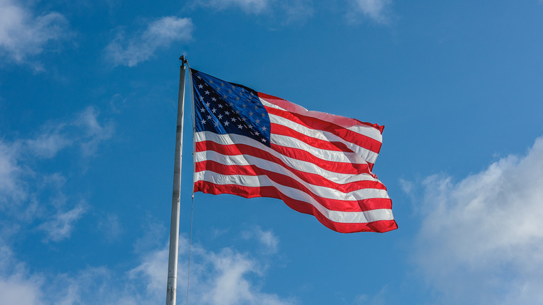 An American flag flying against a blue sky with clouds