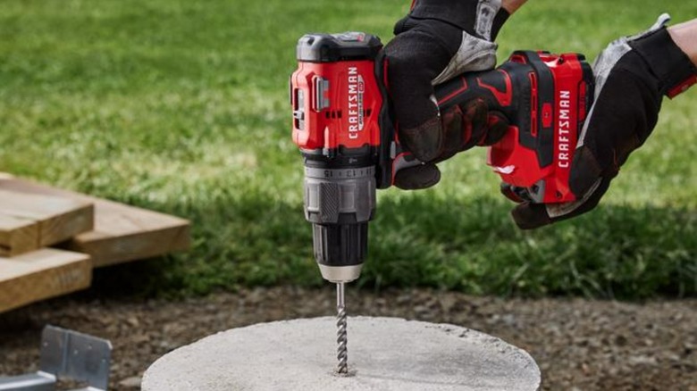 A person drilling into concrete with a Craftsman drill