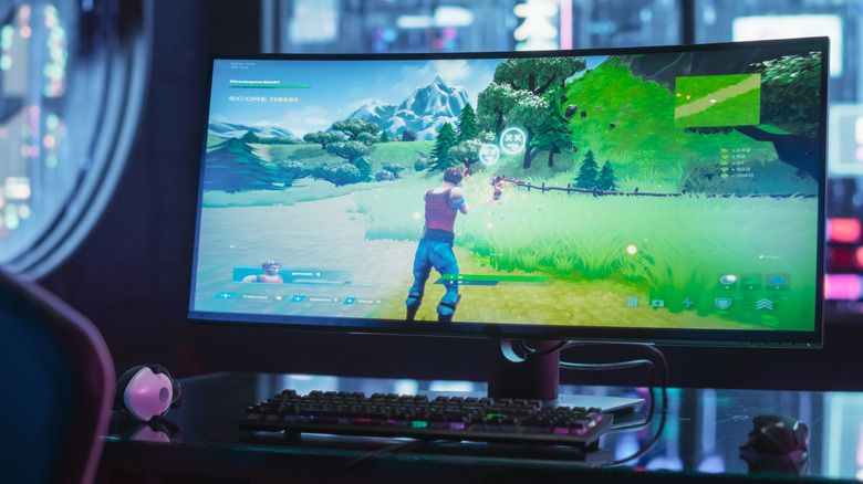 PC Gaming setup with a curved monitor on a desk playing Fortnite