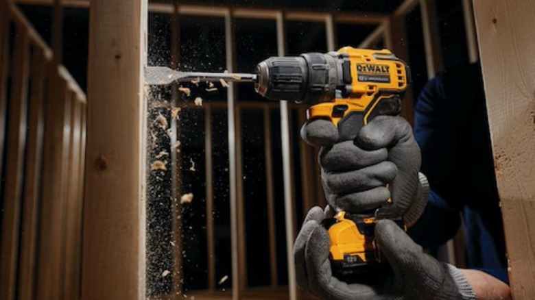 Using DeWalt's 12V drill and a spade bit to drill a hole in a board.