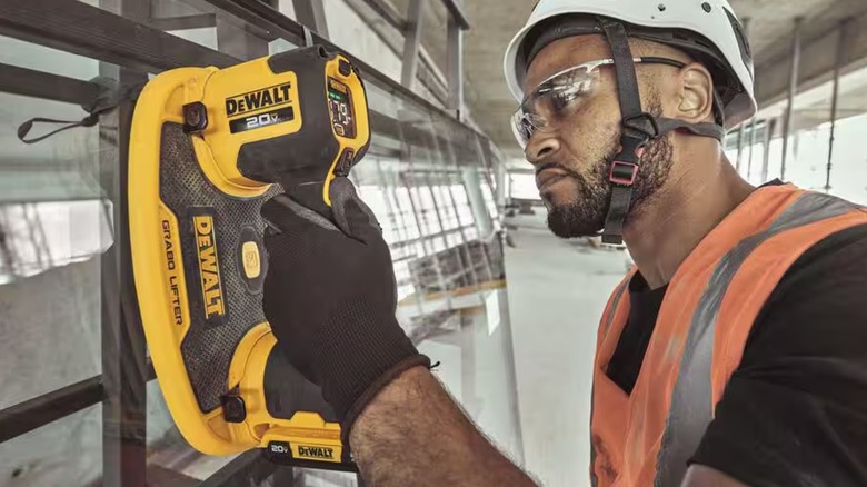 A construction worker using the DeWalt GRABO Lifter on a sheet of glass.