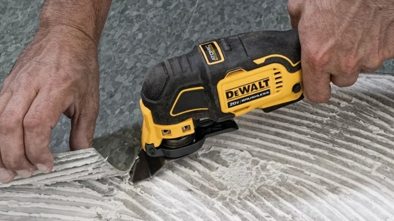 Person using DeWalt Multi-tool to remove grouted flooring
