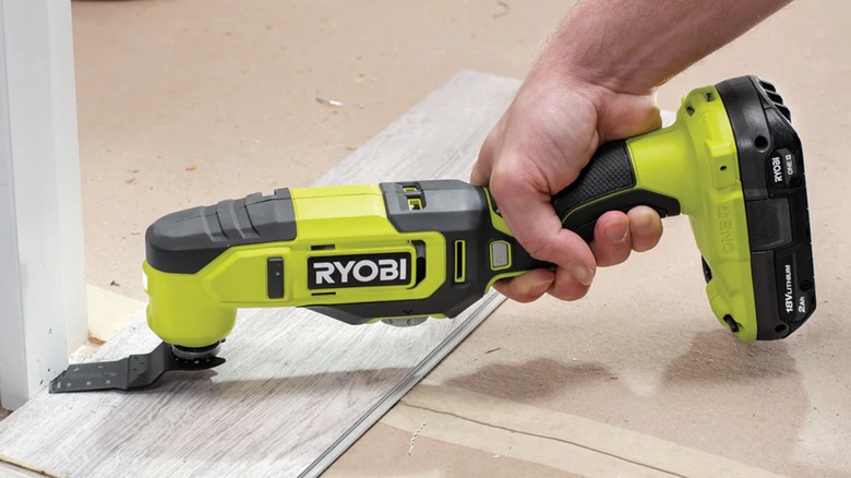 A person uses a Ryobi 18V ONE+ Oscillating Multi-Tool.