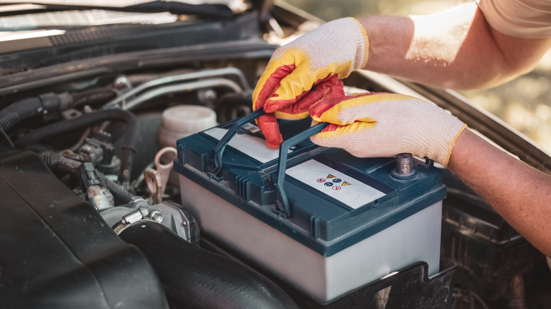 Car battery being placed under hood