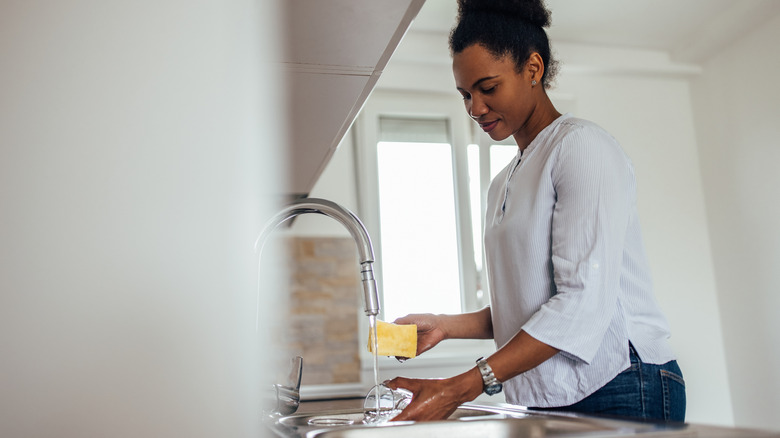 Woman washing dishes in sink