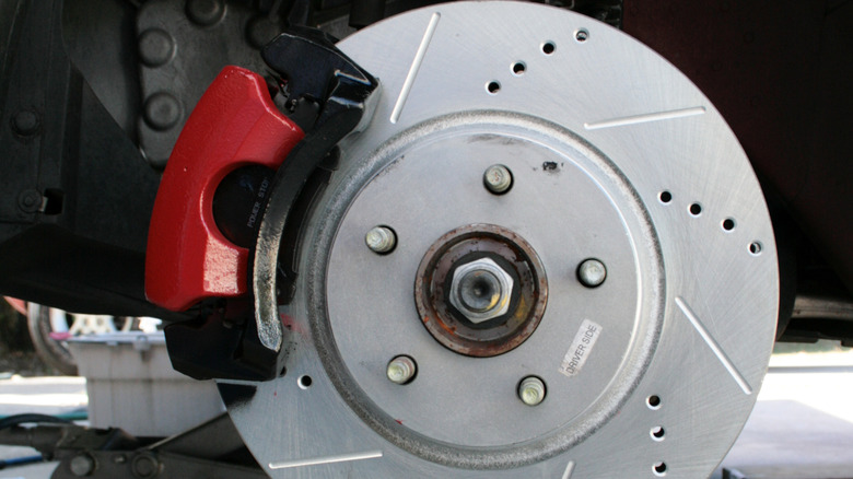 A close picture of drilled and slotted rotors attached with red calipers