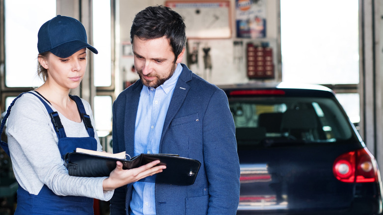 Auto mechanic talking with customer in garage