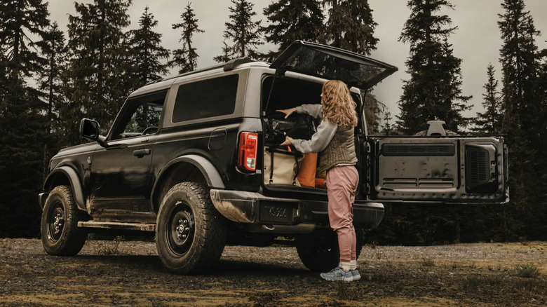 A person loading a Ford Bronco with camping gear