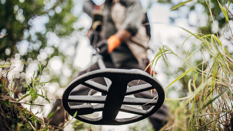 A man treasure hunting on a field with a metal detector