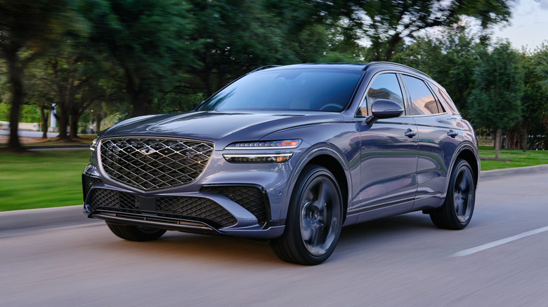 Navy 2026 Genesis GV70 driving down the road, front 3/4 view