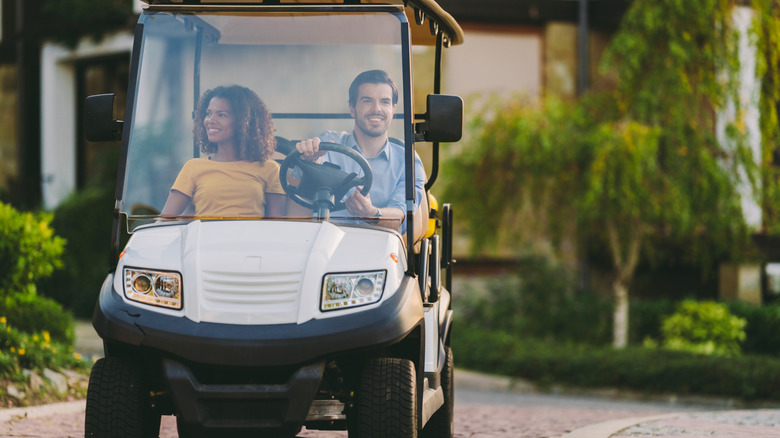 Couple in golf cart driving in hotel entry
