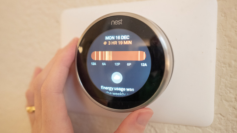 Person adjusting Google Nest thermostat
