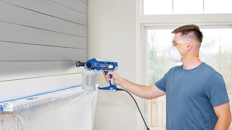 Man using Graco TrueCoat 360 Airless Paint Sprayer to paint a white wall
