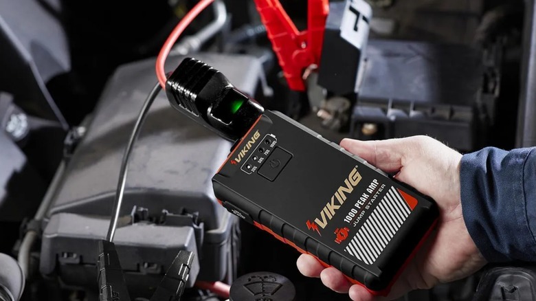 a person using a harbor freight viking jump starter on their car