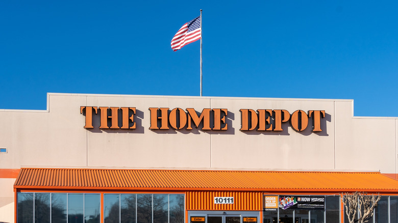 "The Home Depot" sign in orange on front of store building with American flag above it