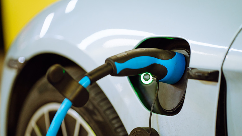 A close-up of the charge port on a Porsche Taycan with a charger plugged in