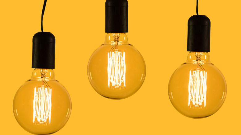3 glowing vintage incandescent filament bulbs, hung at different heights