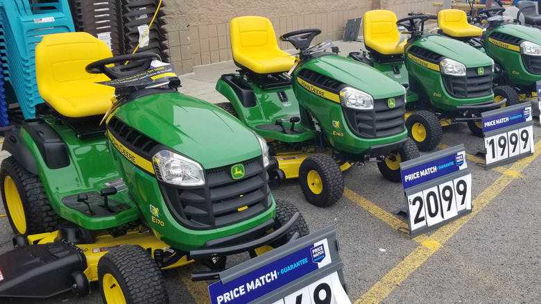 A collection of John Deere mowers outside of a retail store