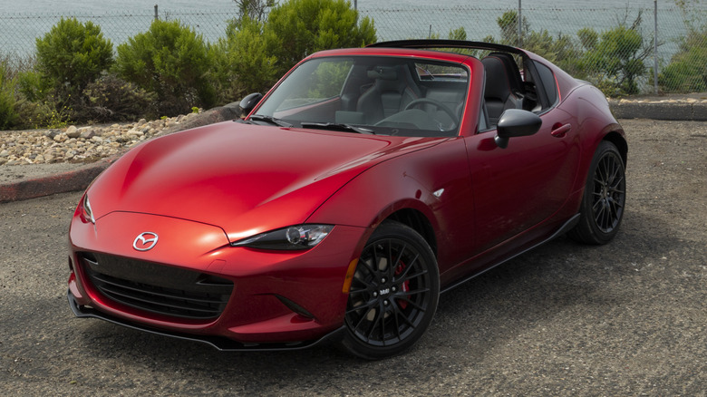 A red Mazda MX-5 Miata parked seaside with its roof down
