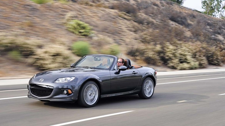 2015 Mazda MX-5 Miata driving along desert road, front-left 3/4 view