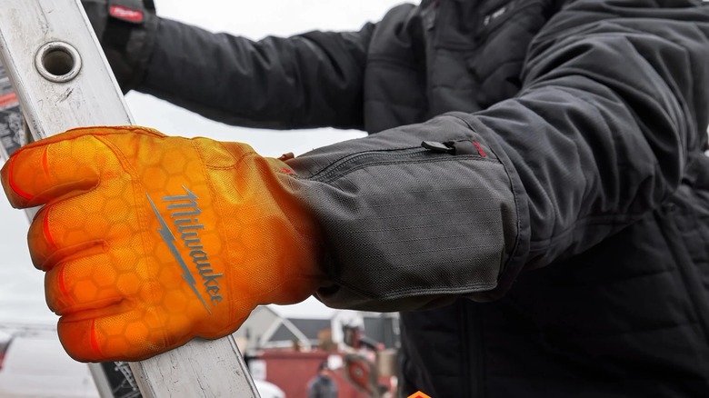 A close up shot of Milwaukee gloves glowing bright orange and gripping a ladder