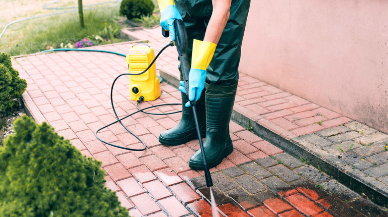 Pressure Cleaning with High Pressure Washer Karcher in Garden Park or Street.