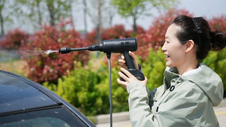 A woman washing her car with a Portable Pressure Washer