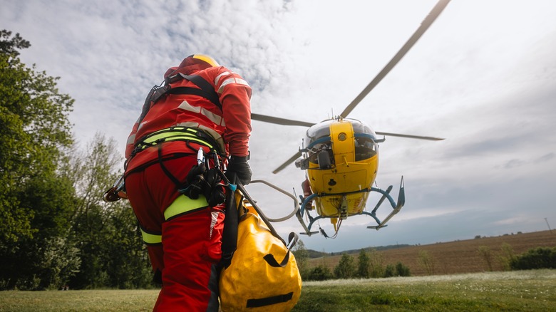 Aterrizaje de helicóptero de rescate amarillo en campo con trabajador
