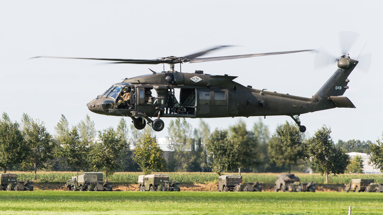 Military helicopter hovering over a field