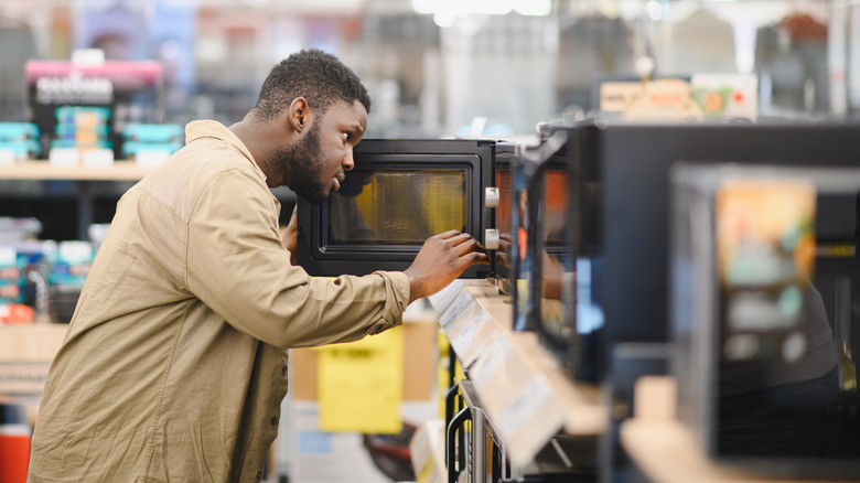 A guy choosing a new microwave at the store