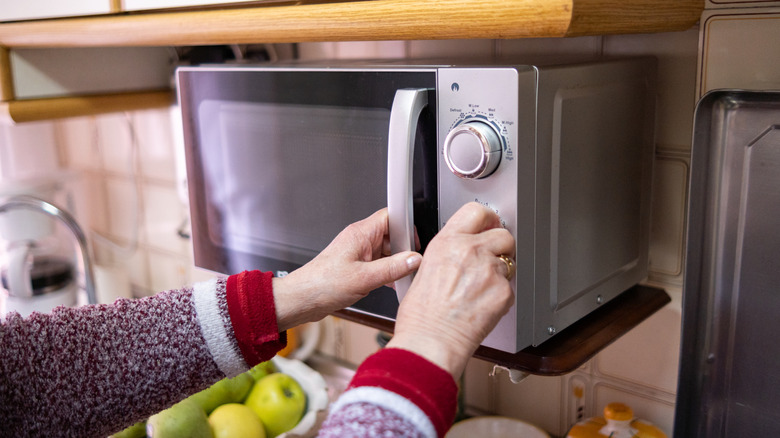 A woman closing a microwave in her kitchen