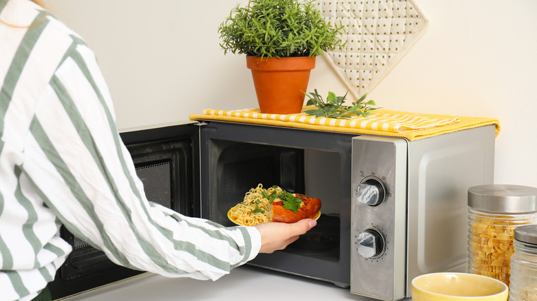 A person putting food inside a microwave