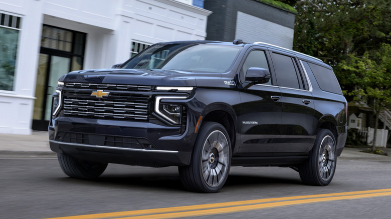 A black Chevrolet Suburban motors down a suburban street.