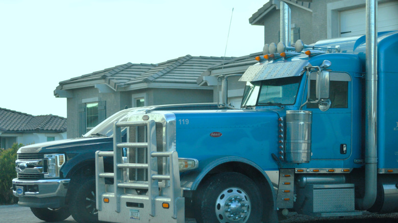 Blue Peterbilt semi-truck parked in front of residential garage