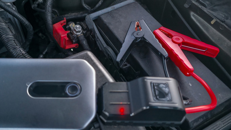 A portable jump starter sitting near a car battery