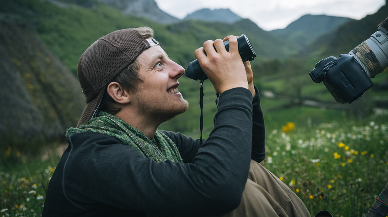 smiling man using binoculars