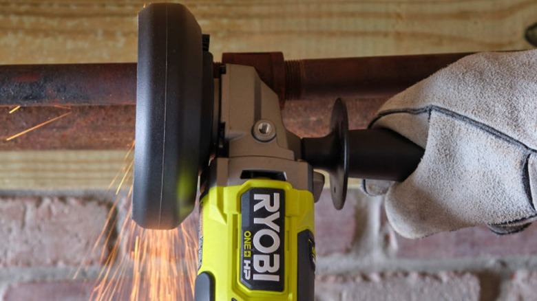 Person using Ryobi Angle Grinder on pipe