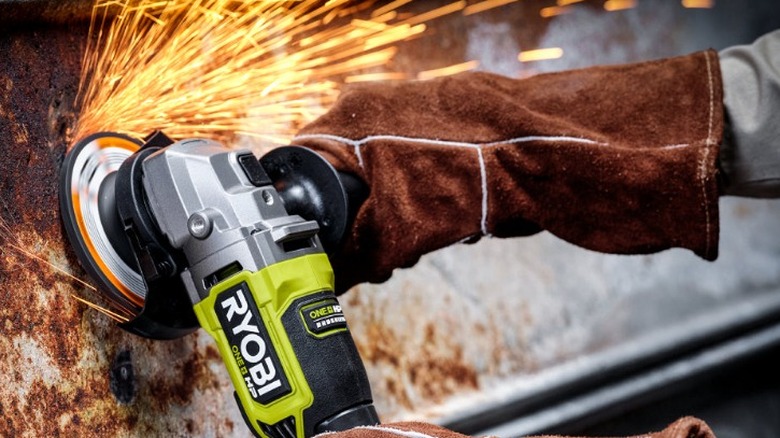 Person using Ryobi Angle Grinder on rusty metal
