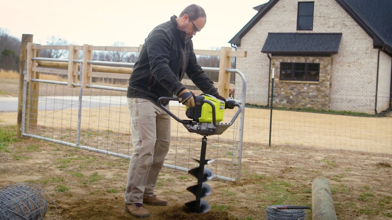 Person digging hole with Ryobi Auger