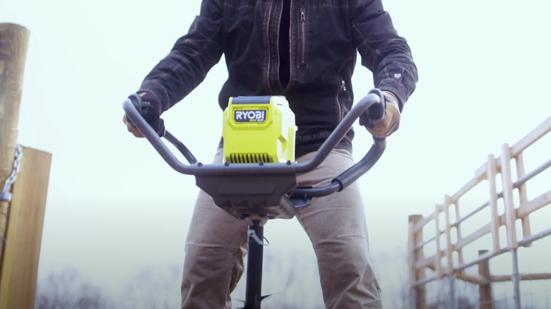 Person digging hole with Ryobi Auger
