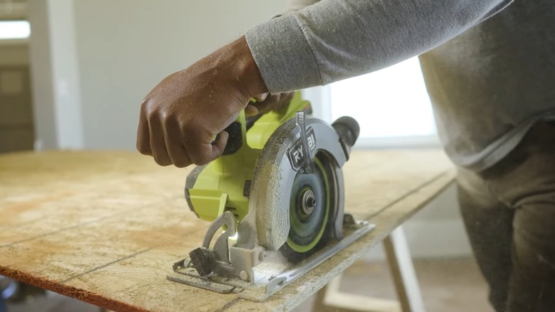 A person using a Ryobi circular saw with Ryobi blade to cut wood