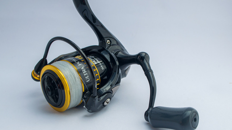 A black and gold Ryobi fishing reel lying on a white surface