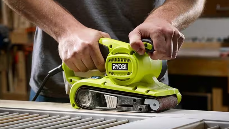 Person holding a Ryobi belt sander