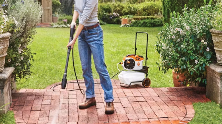 Woman using Stihl pressure washer in the yard