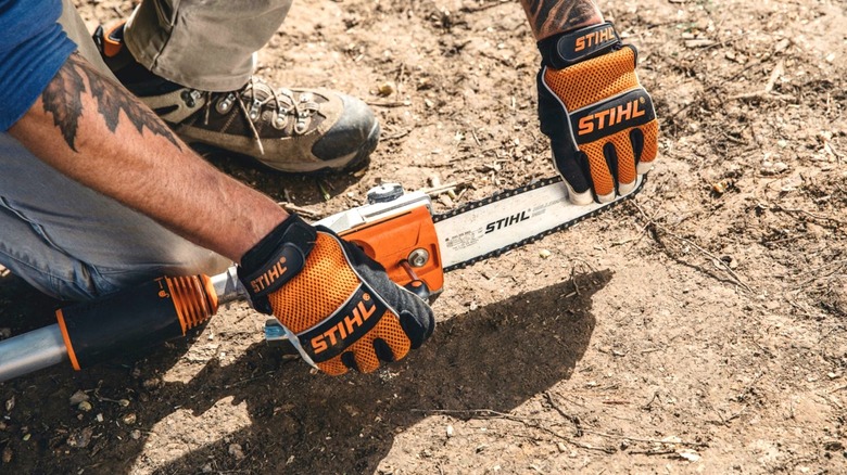Person inspecting the chain on a Stihl pole saw