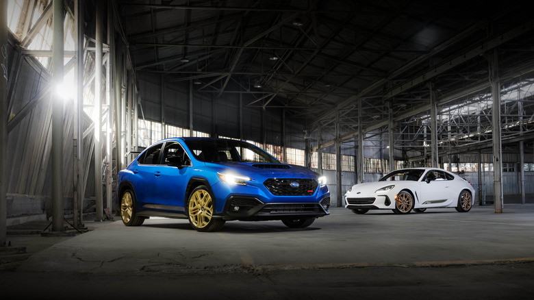 2026 Subaru Impreza (left foreground, front-right 3/4 view) and Subaru BRZ (right background, front-left 3/4 view) inside industrial building