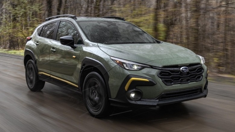 Subaru Crosstrek Sport driving down a road with trees in the background