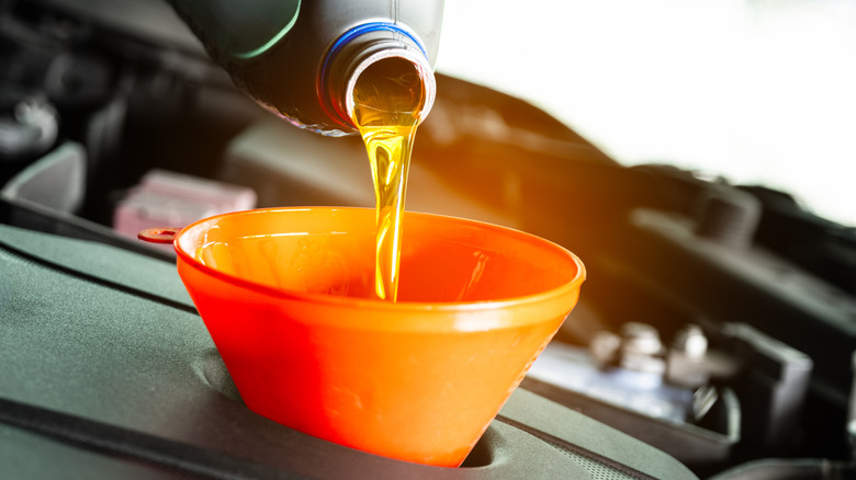 Car oil being poured into orange funnel
